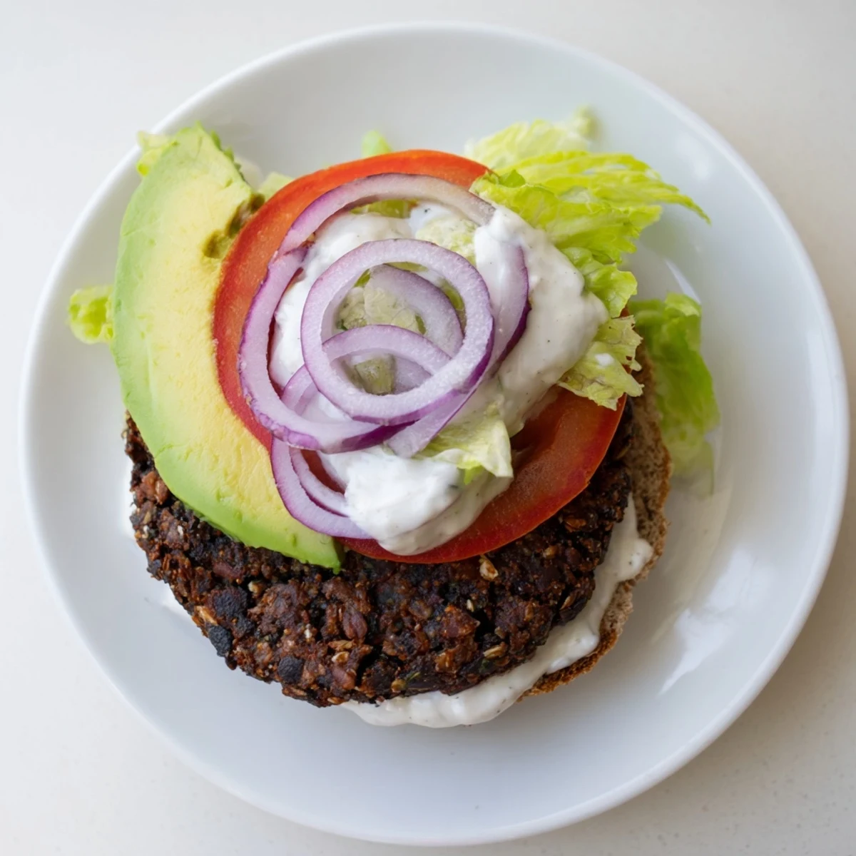 Steaming, juicy Zesty Black Bean Burgers topped with fresh avocado and vibrant red onion, ready to eat.