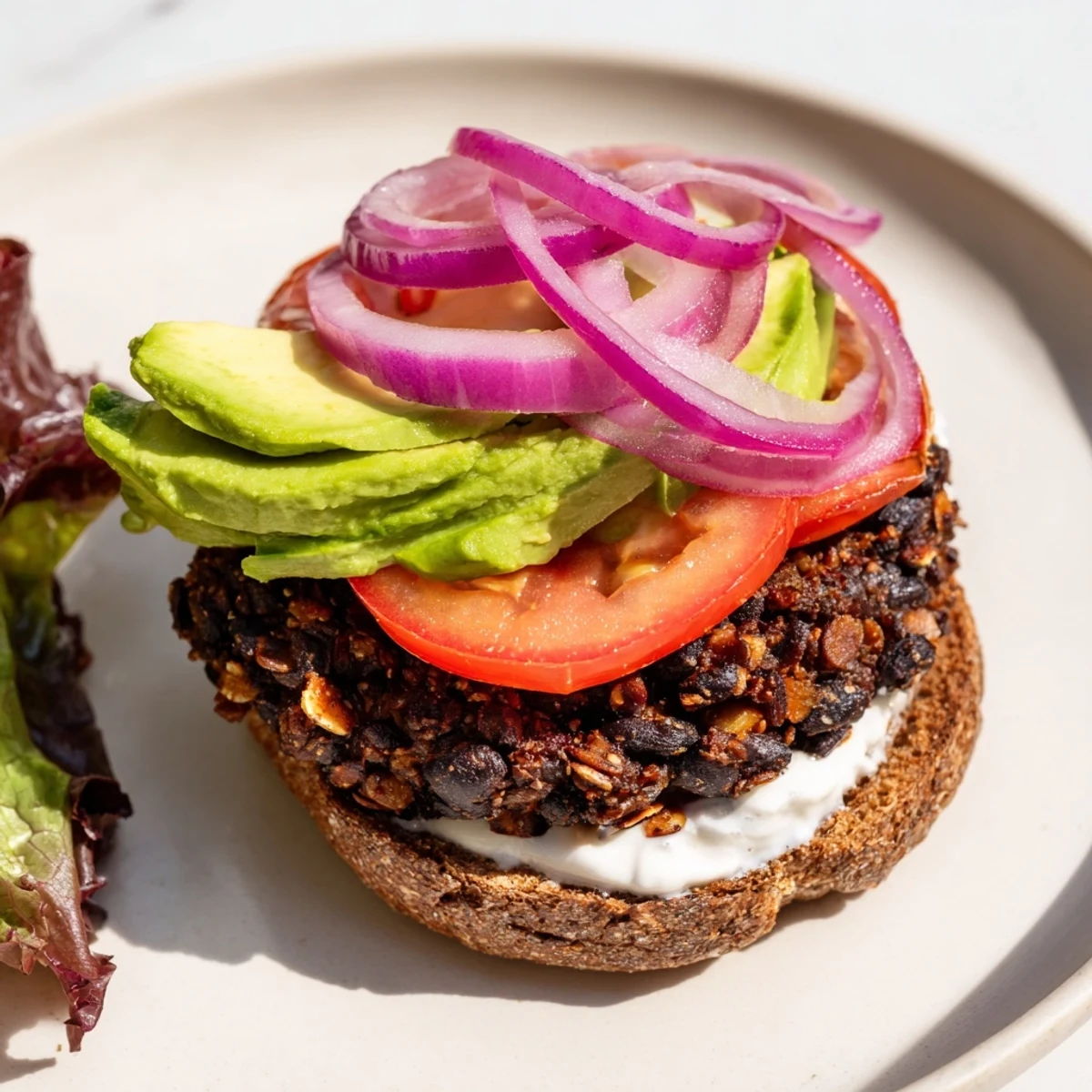 Delicious Zesty Black Bean Burgers feature a perfectly grilled patty, piled high with fresh avocado slices.