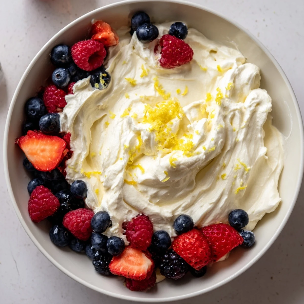 Enjoy a bowl of refreshing fluffy cream cheese fruit dip, served with juicy, ripe berries.