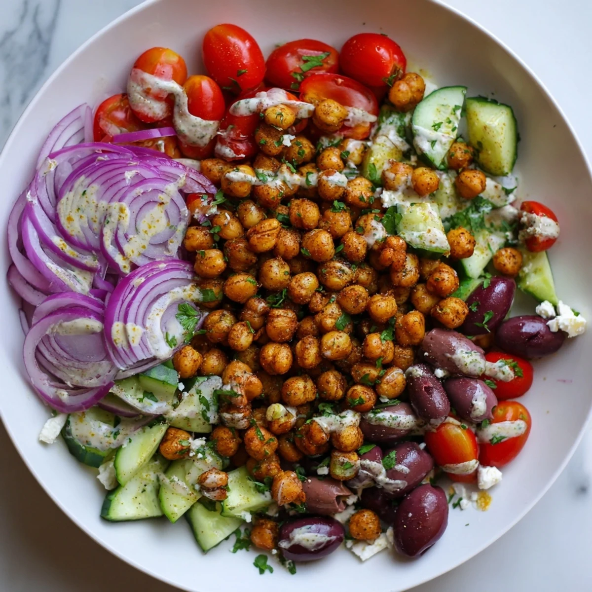 Crispy roasted chickpeas star in this vibrant Mediterranean chickpea bowl, drizzled with tahini.