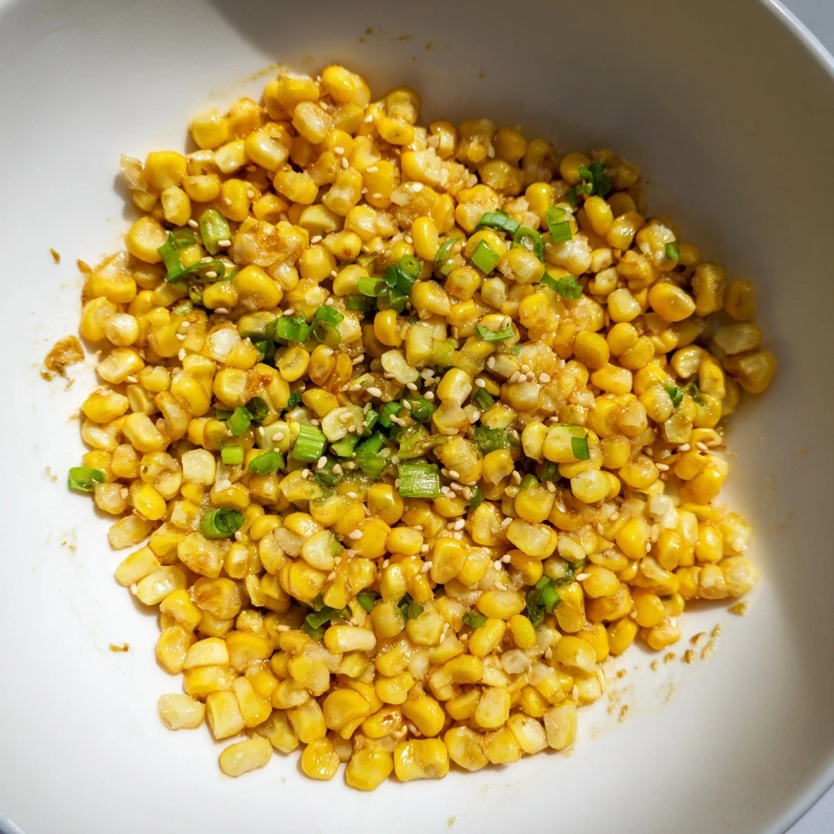 Steaming bowl of delicious Japanese Butter Corn, ready to serve with scallions, sesame seeds, and soy sauce.
