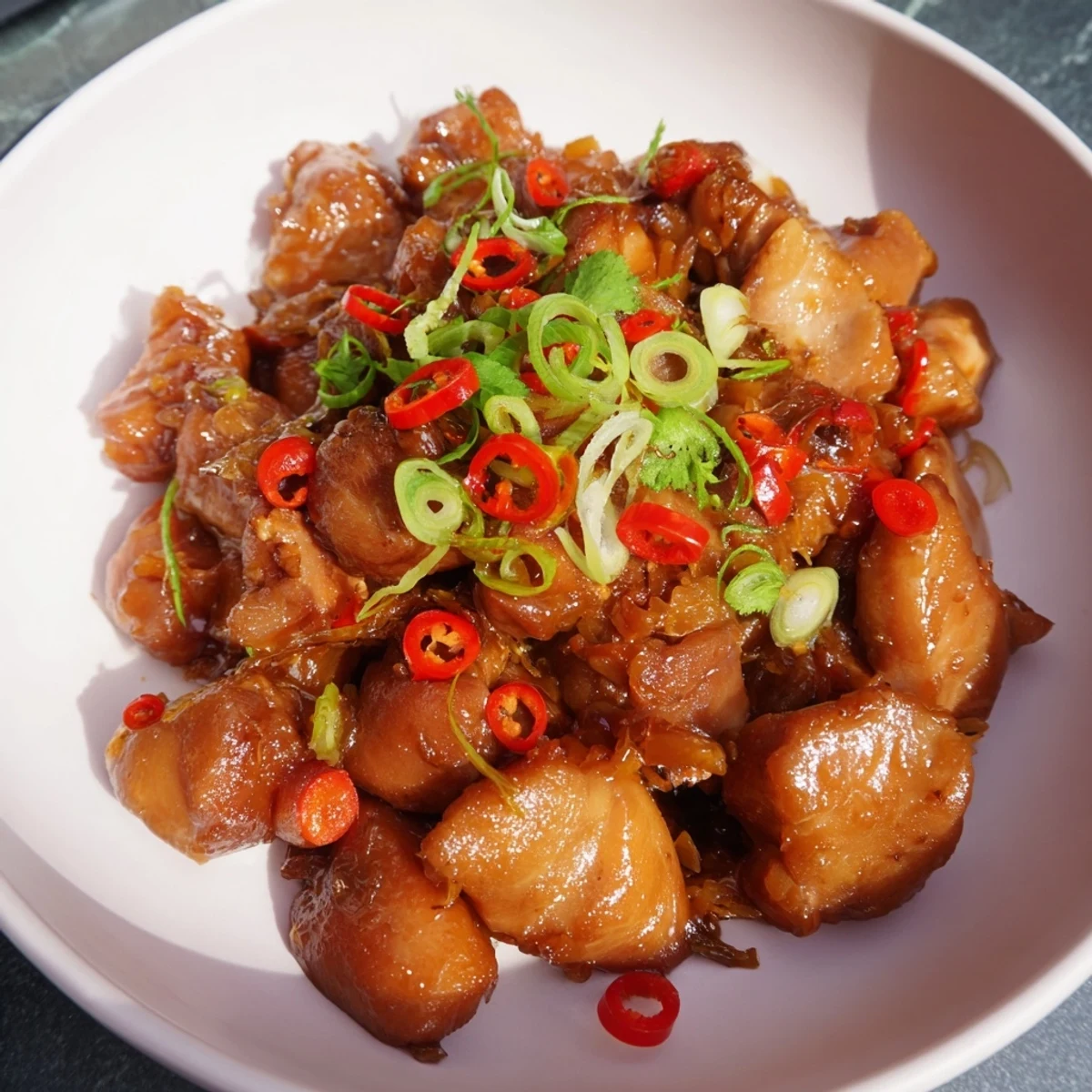 Close-up of sticky-glazed Vietnamese Caramel Chicken, garnished with fresh herbs offering a savory aroma.