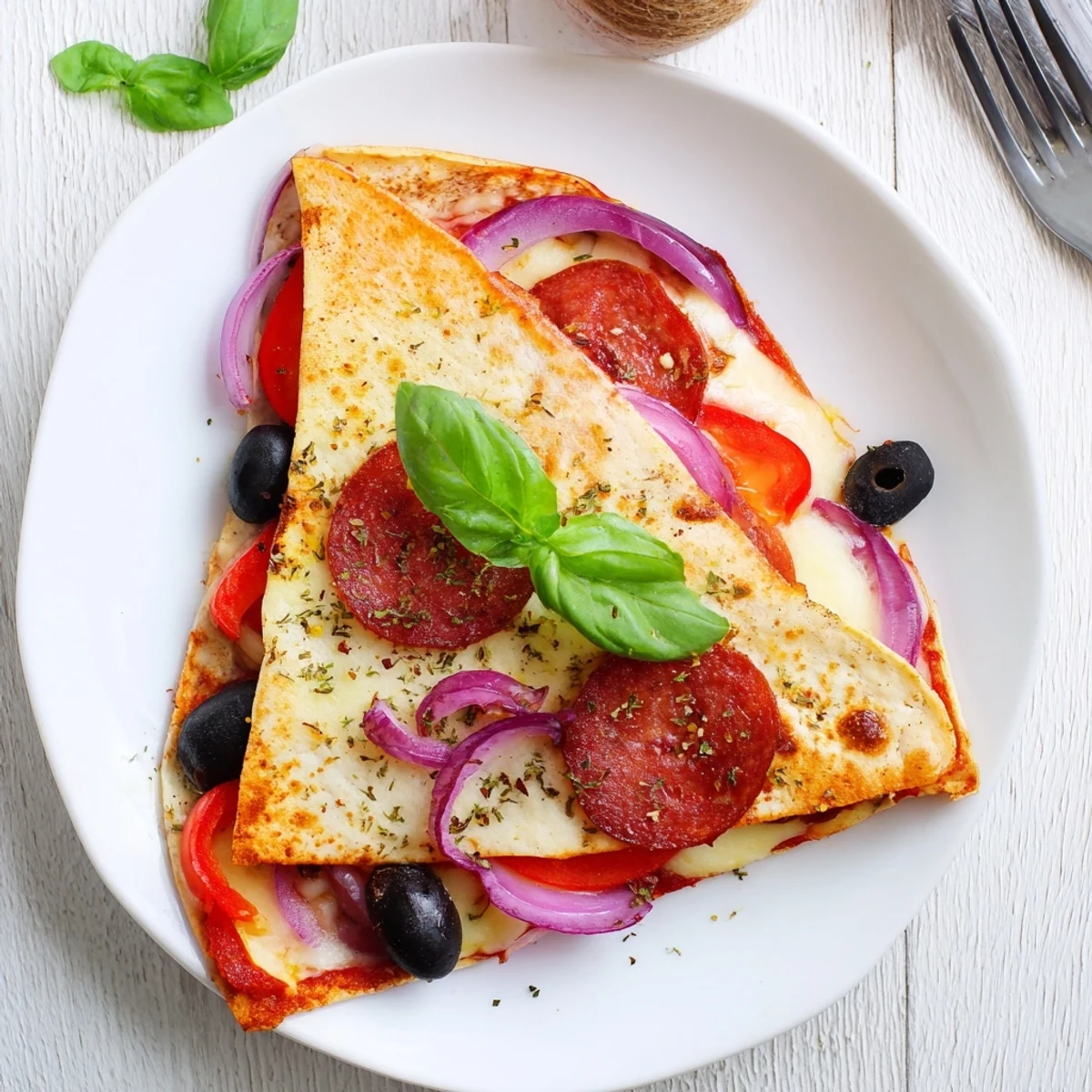 A close-up of a triangular, pan-toasted tortilla pizza wrap with vibrant bell peppers, olives, and melty cheese.
