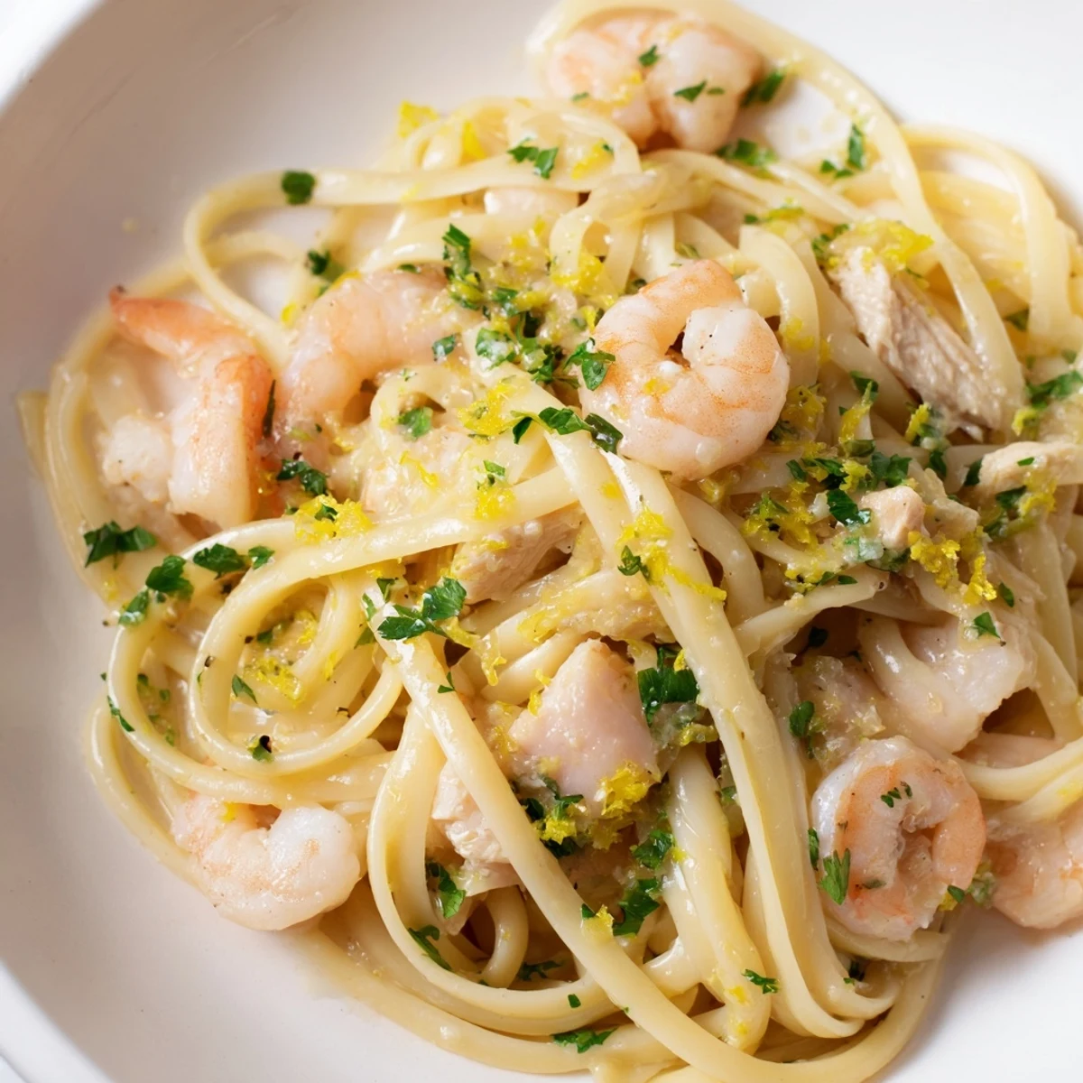 Fork twirling through strands of linguine coated in zesty lemon-garlic butter sauce with tender chicken and succulent shrimp.