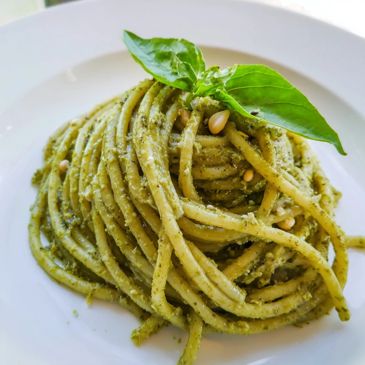 A close-up of Creamy Sunflower Seed Pesto Pasta with vibrant green sauce and fresh basil garnish, steaming on a rustic wooden table.