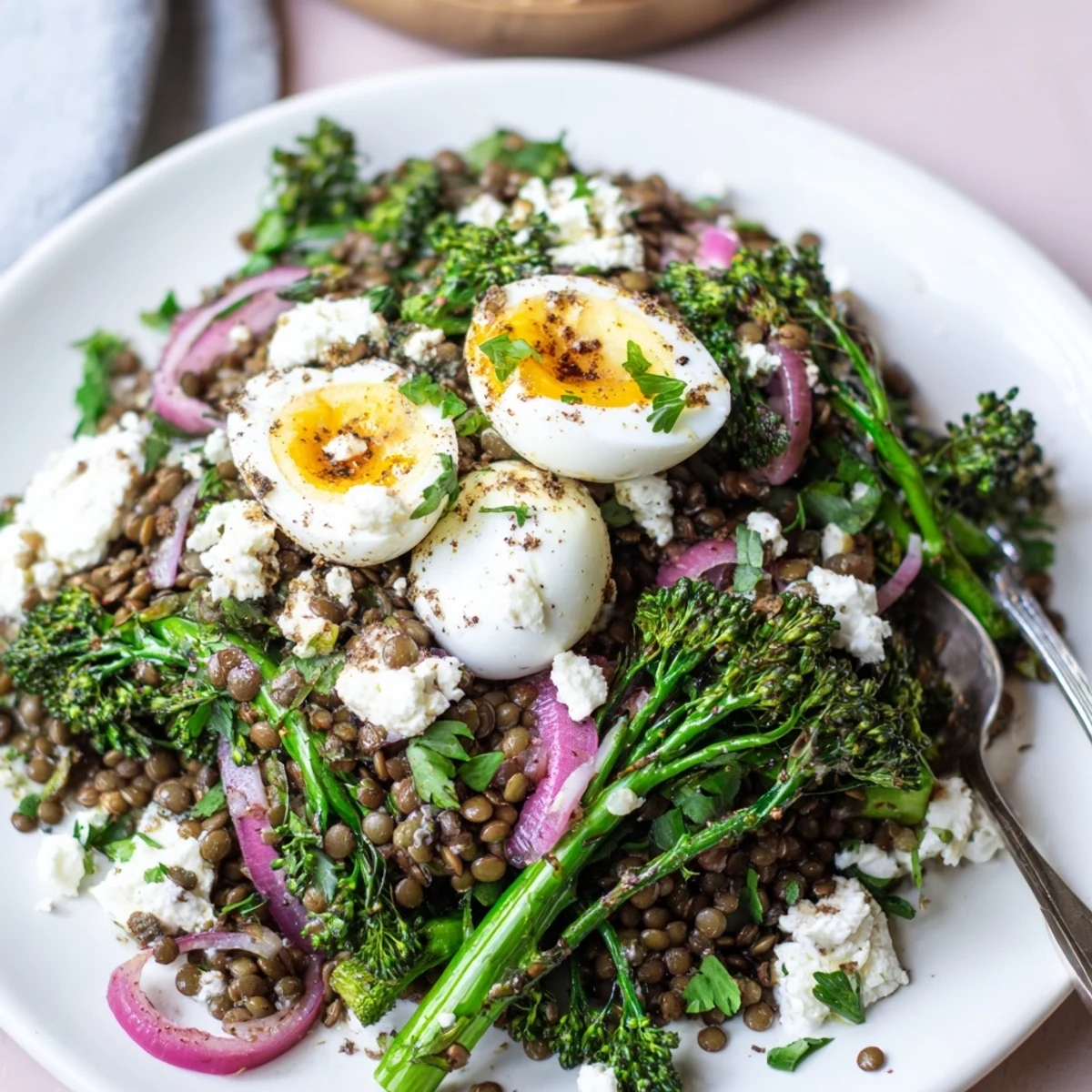 French Lentil Salad With Broccolini and Soft-Cooked Eggs garnished with crumbled goat cheese and fresh parsley.