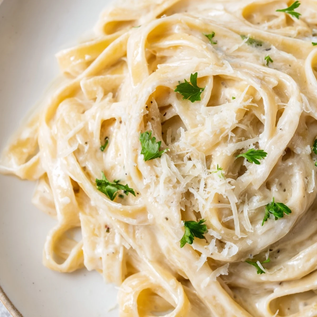 Roasted garlic cream pasta in a skillet, close-up of silky sauce coating al dente noodles.