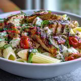 Bright cherry tomatoes soften around tender chicken and pasta tossed with basil, mozzarella, and balsamic in a skillet of Bruschetta Chicken Pasta.