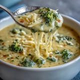Rich and cheesy broccoli cheddar soup featuring fresh broccoli and smooth cheddar cheese, served hot in a rustic bowl.  