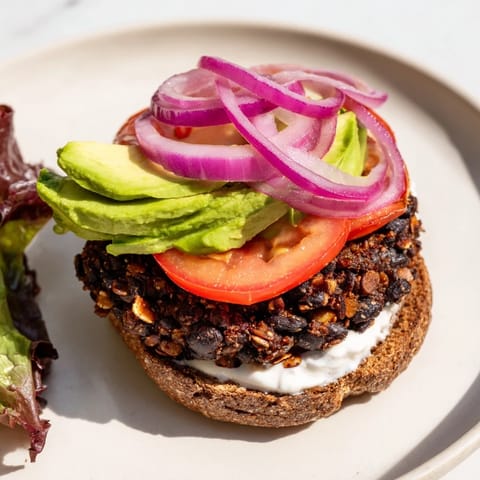 Delicious Zesty Black Bean Burgers feature a perfectly grilled patty, piled high with fresh avocado slices.
