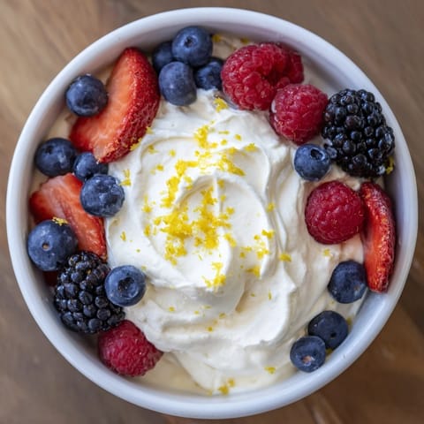 A close-up of fluffy cream cheese fruit dip with vibrant berries, a perfect easy snack.