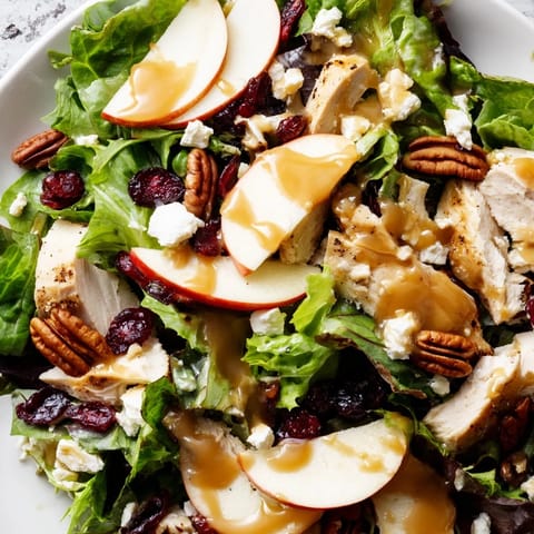 Sliced Honeycrisp apples and tender chicken breast fill this Caramel Apple Chicken Salad, garnished with dried cranberries and crumbled feta on fresh greens.