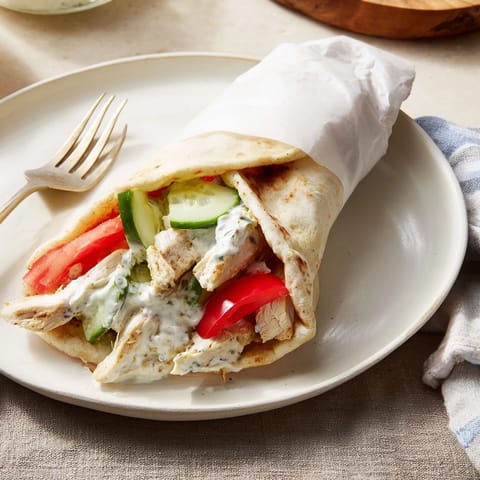 Savory Greek Chicken Wrap with juicy grilled chicken, ripe tomato slices, and a generous swirl of tzatziki.
