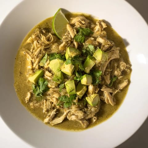 Hearty Chicken Chili Verde simmers in a Dutch oven, releasing aromatic scents of charred peppers and cumin in a rich, tangy broth.  