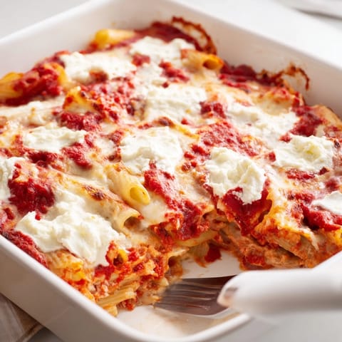 A slice of hearty Freezer Make-Ahead Baked Ziti shows creamy ricotta layers and savory Italian sausage in a casserole dish.