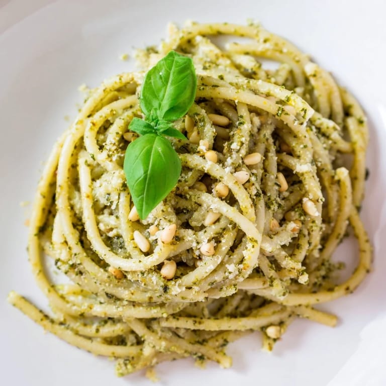 A beautiful bowl of Creamy Sunflower Seed Pesto Pasta garnished with fresh basil leaves, showcasing the creamy texture and golden toasted seeds.