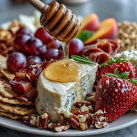 Summer charcuterie board with fresh fruit, honey, meats, and cheeses.